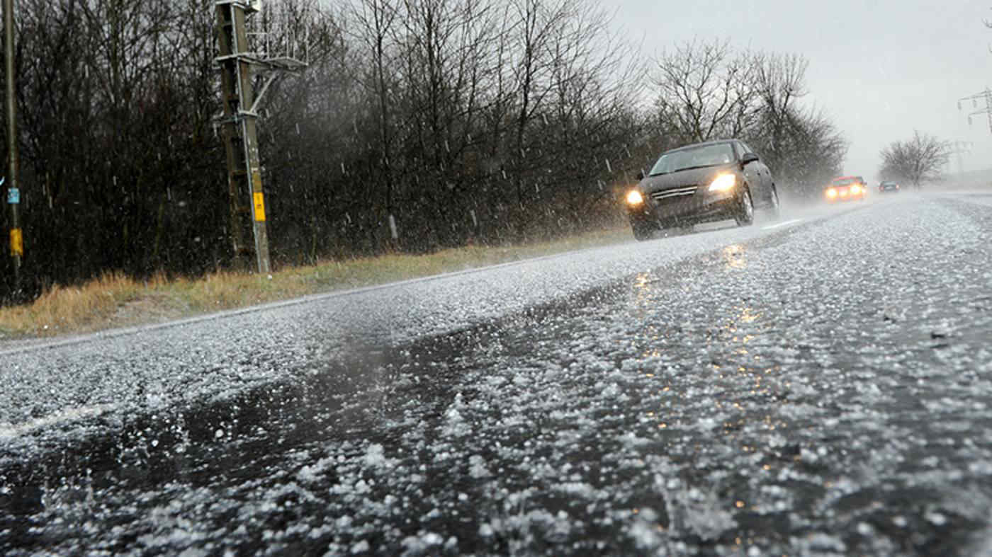 Automobile marciante su asfalto ricoperto di grandine